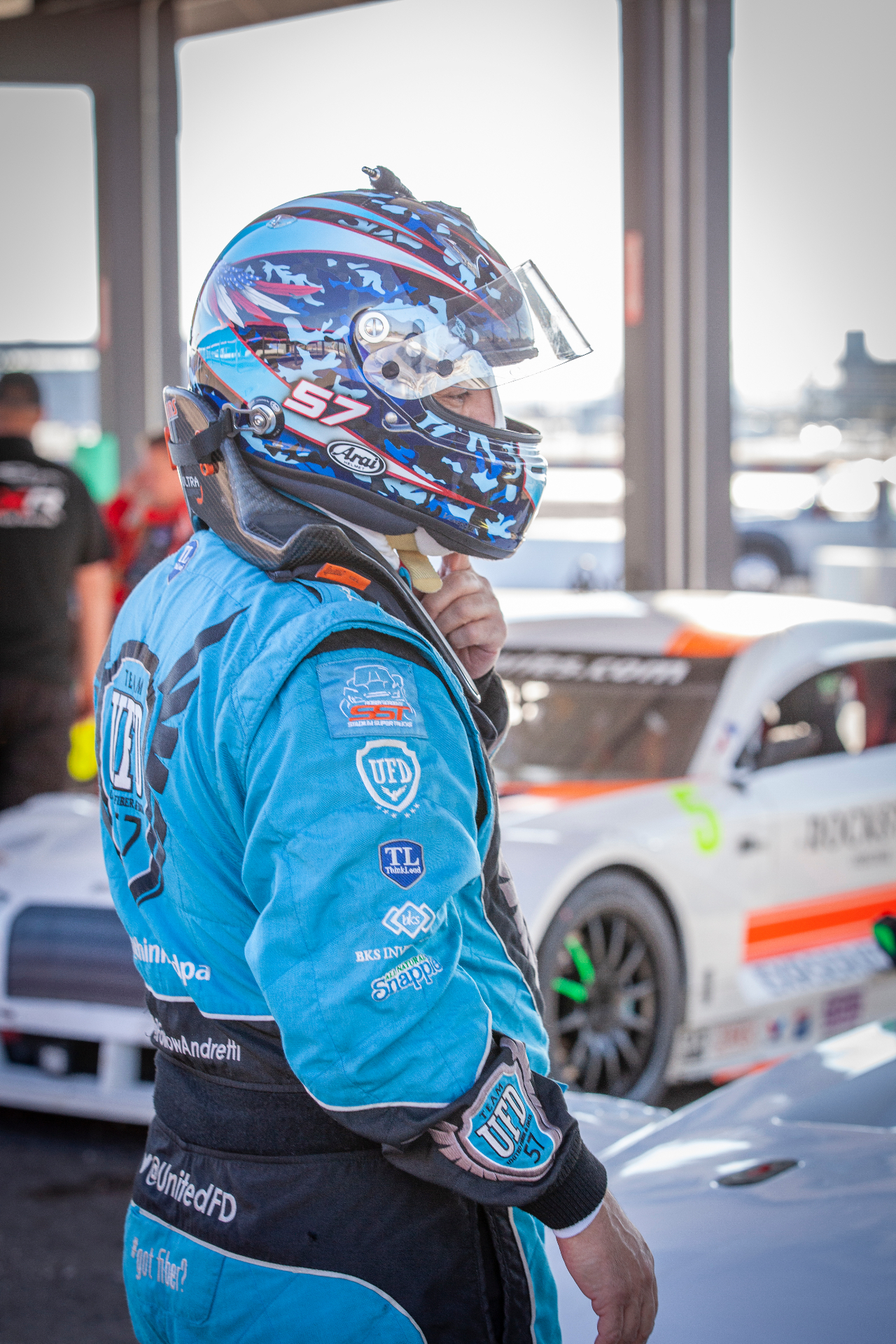 Bill Hynes in racing helmet and suit beside race car